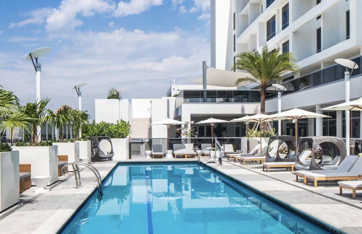 Hilton Aventura Miami with a big swimming pool with white tables
