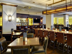 Restaurant interior with bar and wooden tables.