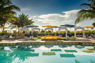 Tropical poolside with cabanas and umbrellas.